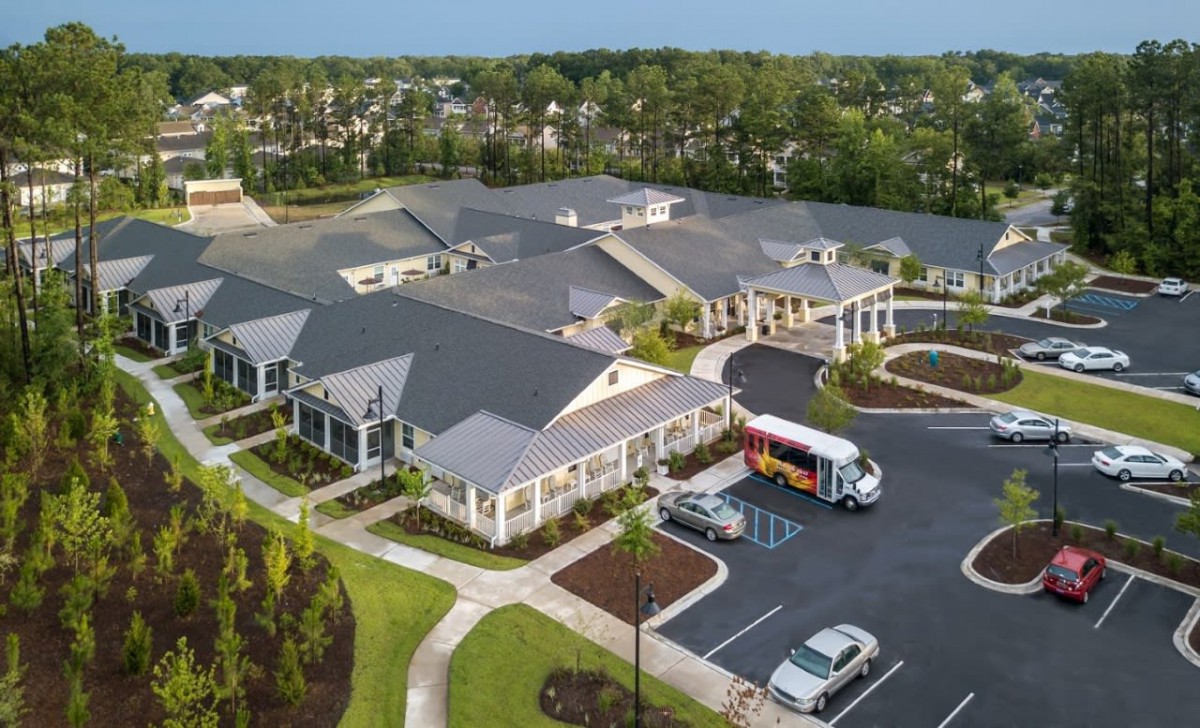 An aerial view of a large building with a parking lot and surrounding greenery.