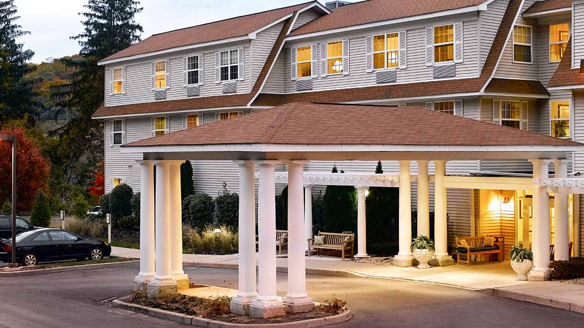 The exterior of a hotel featuring a covered entrance with columns and warm lighting.