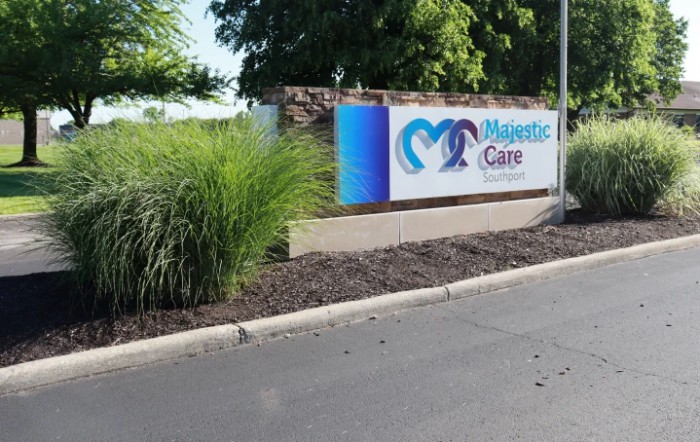 A healthcare facility sign with landscaping along a road.