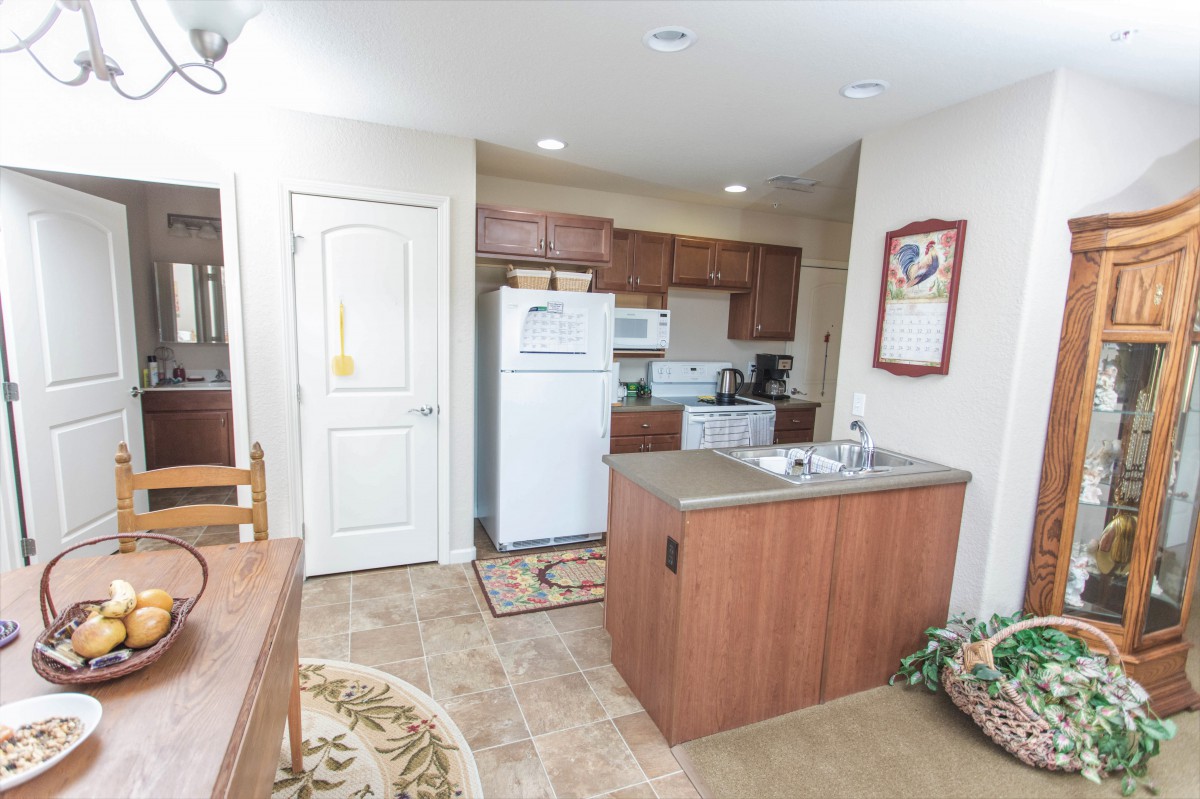 A cozy kitchen interior with wooden cabinets, a refrigerator, and a small dining area.