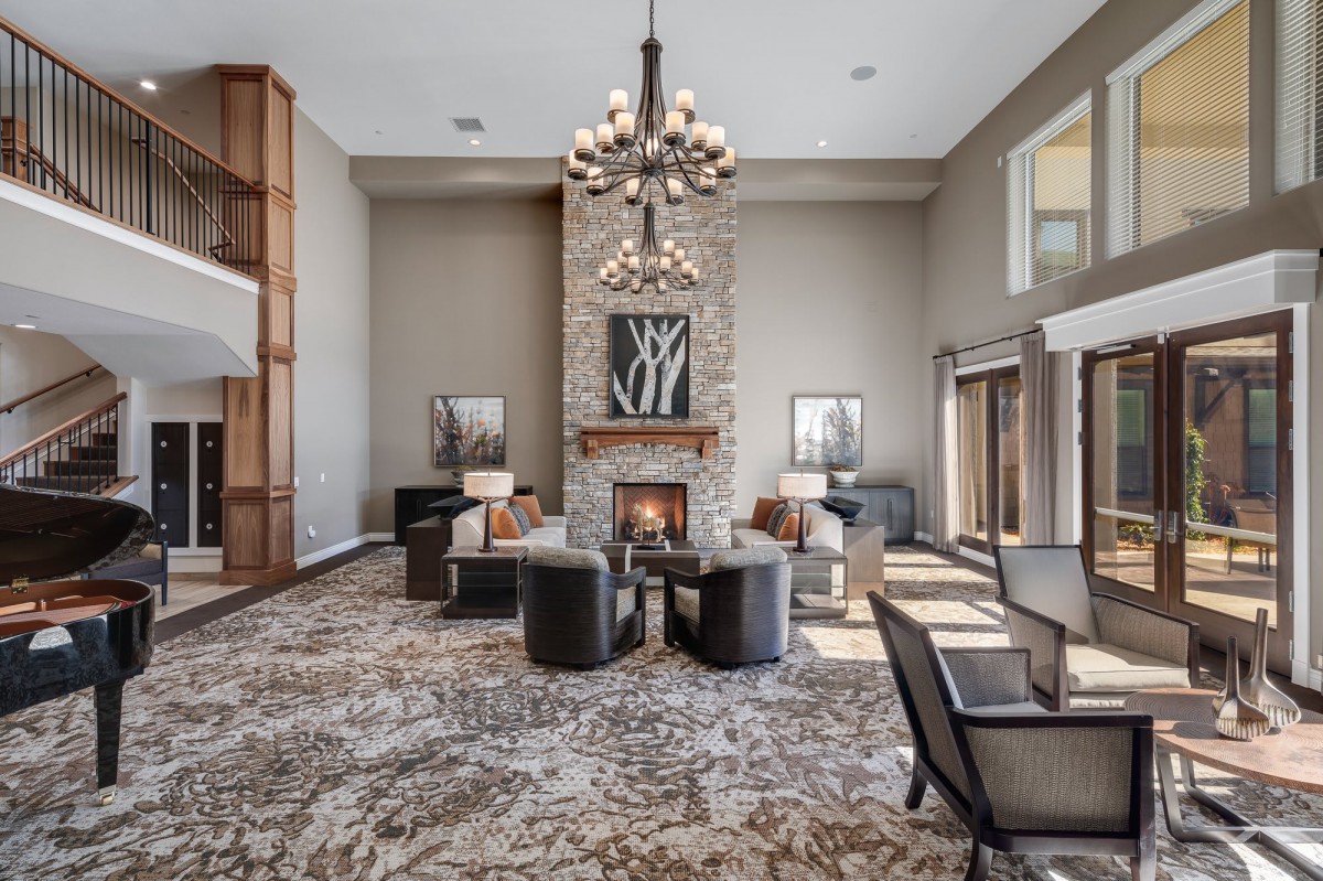 A luxurious living room features a grand chandelier, modern seating around a cozy fireplace, and elegant interior design.