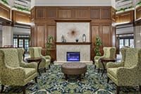 A cozy lobby with elegant chairs, a fireplace, and decorative plants.