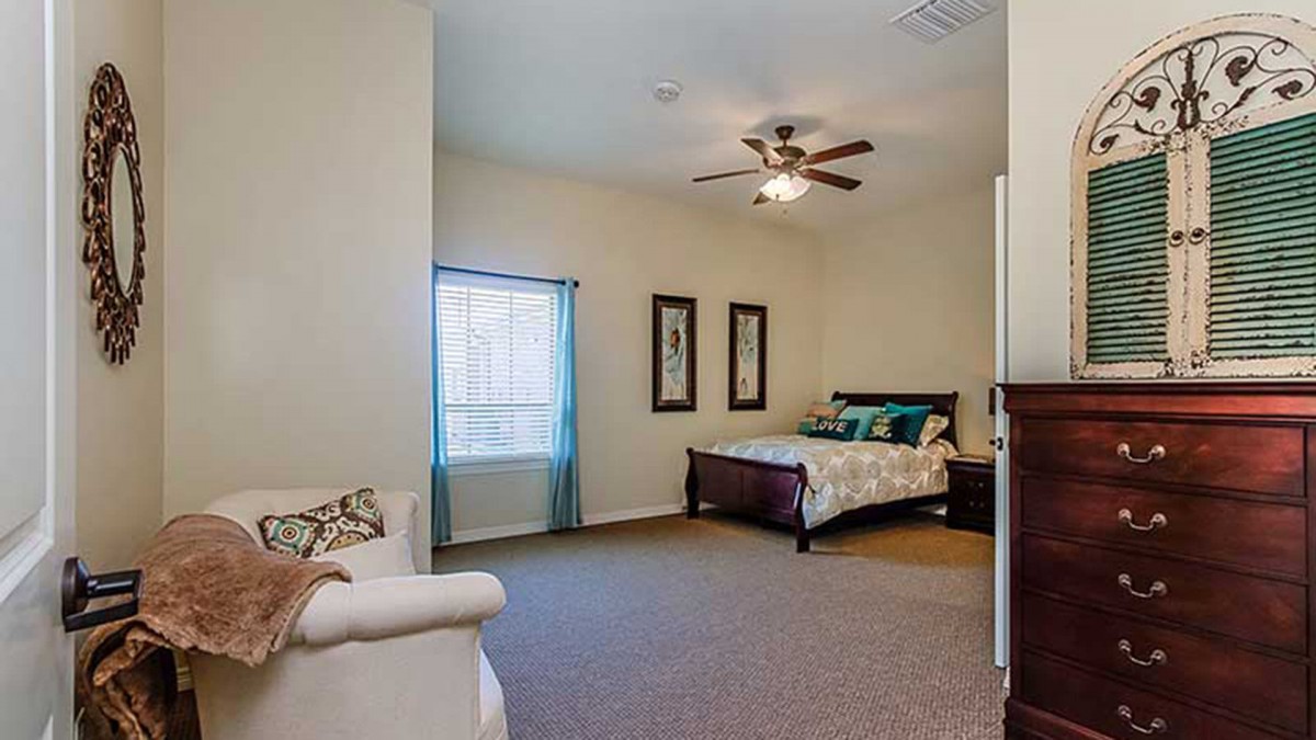A cozy bedroom featuring a bed, ceiling fan, and window with curtains.