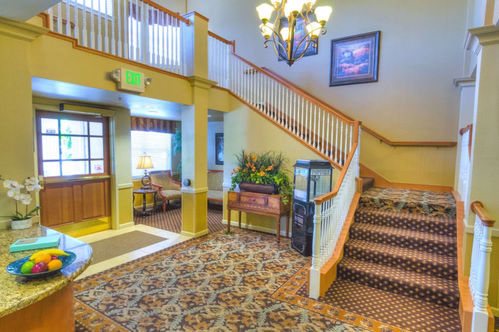 A cozy hotel lobby featuring a staircase and chandelier.