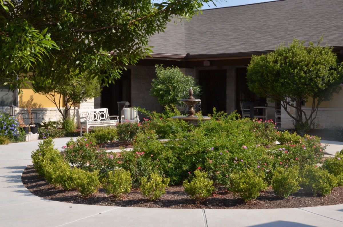 A well-maintained garden with a variety of plants and bushes in front of a building.