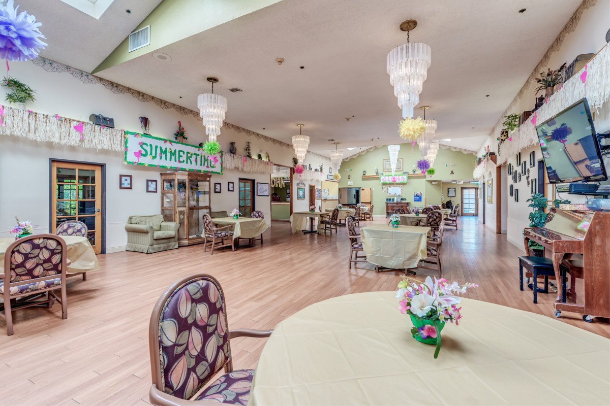 A bright and spacious dining area with decorative chandeliers and floral arrangements on tables.
