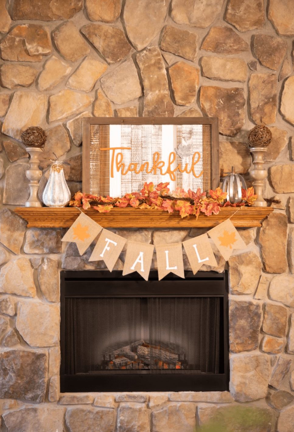 A cozy fireplace adorned with fall-themed decorations, featuring a 'Thankful' sign and autumn leaves.