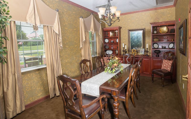 An elegant dining room featuring classic wooden furniture and a central chandelier.