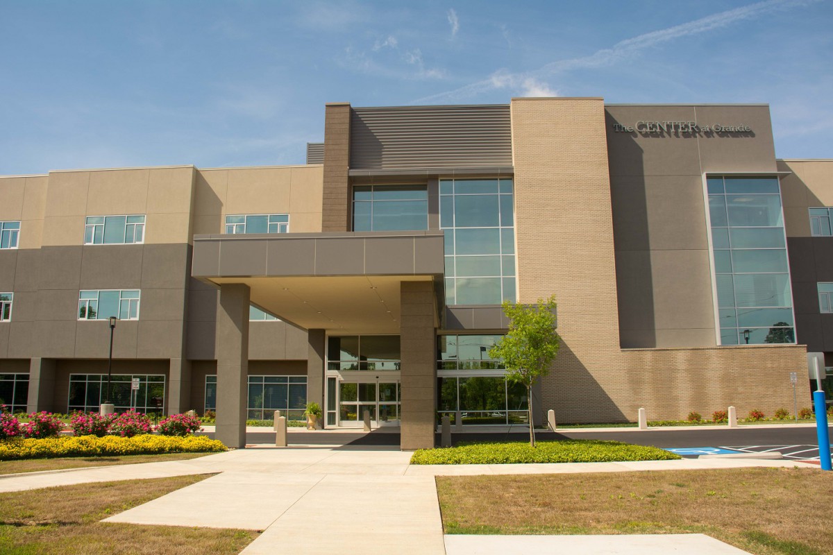 A modern educational building with large windows and landscaped surroundings.
