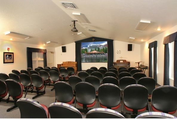 An empty auditorium with rows of chairs facing a screen and stage area.