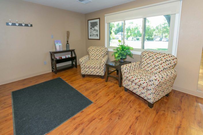 A cozy living room with patterned armchairs and a wooden floor.