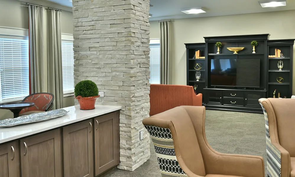 A cozy living room with modern decor featuring a brick accent wall, comfortable armchairs, and a television stand.