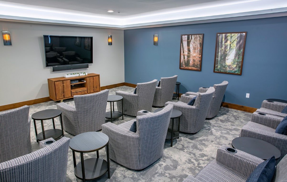 A cozy home theater with multiple seating options and a large television on the wall.