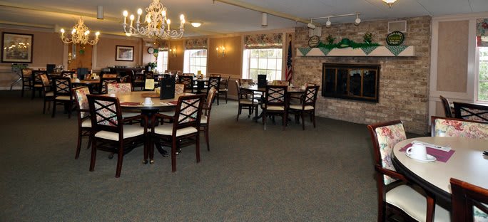 A cozy dining area featuring multiple tables and chairs, a chandelier, and a fireplace.
