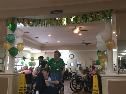 Residents enjoying a festive celebration at a senior living facility, adorned with green balloons and decorations.