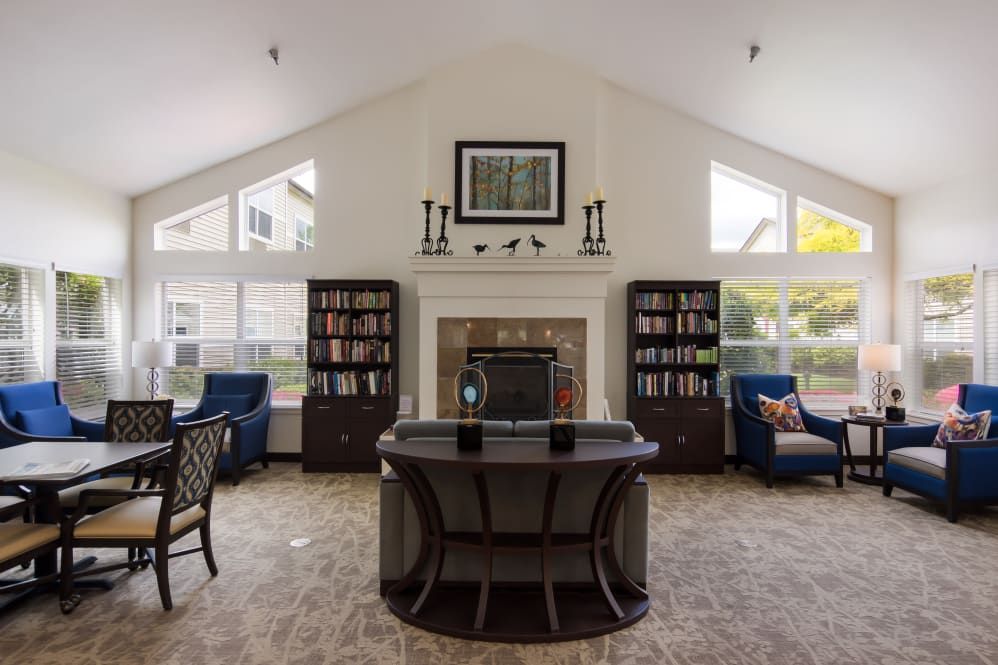 A cozy library room with bookshelves, a central fireplace, and comfortable seating.