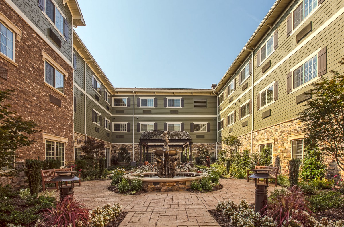 A serene courtyard with a central fountain, surrounded by a multi-story building and well-maintained landscaping.