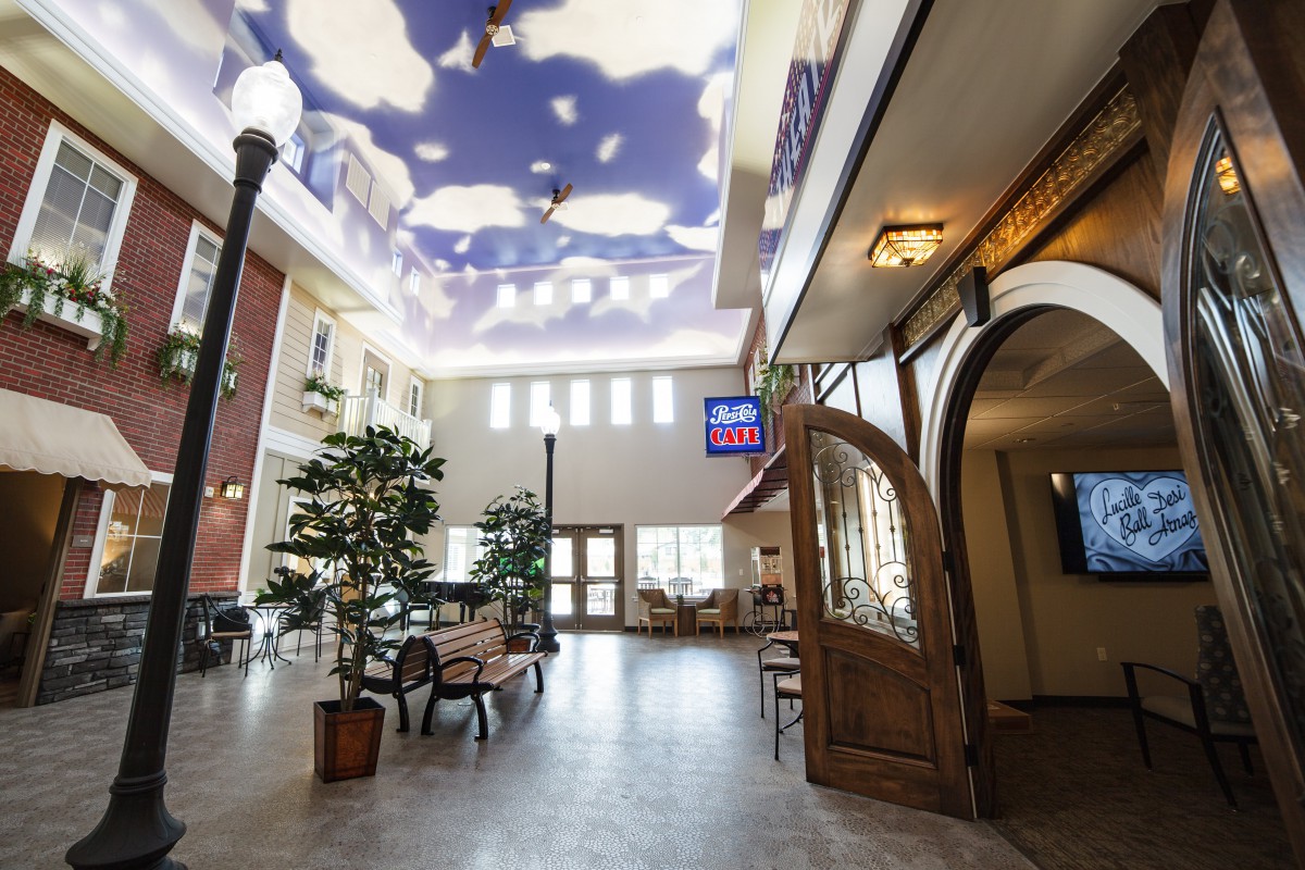 A spacious lobby with a sky-themed ceiling, seating area, and artificial plants.