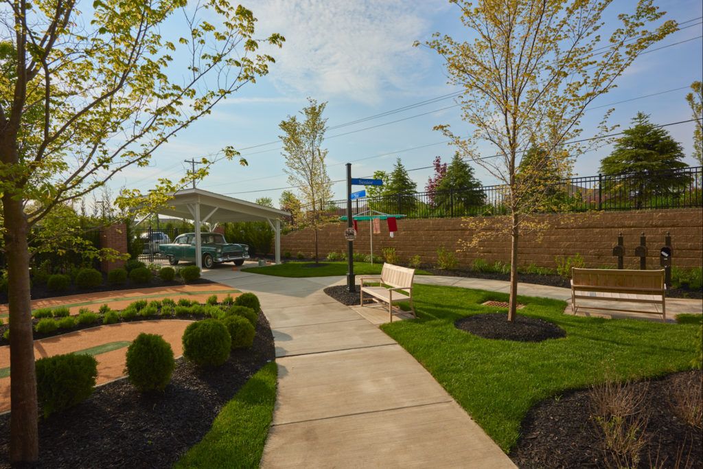 A serene pathway in a well-maintained park with lush greenery and benches.