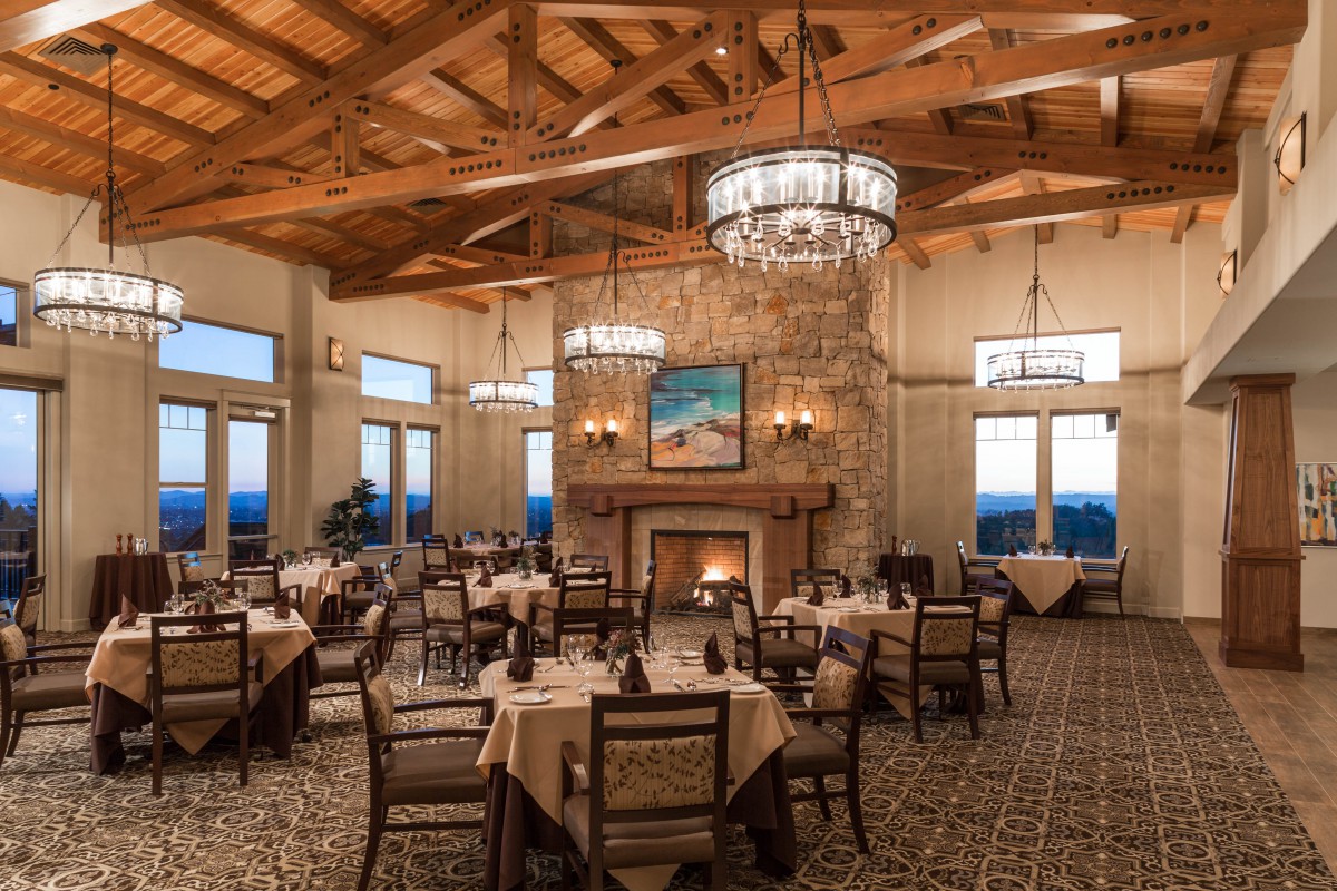 An elegantly designed restaurant dining room featuring chandeliers and a cozy fireplace.