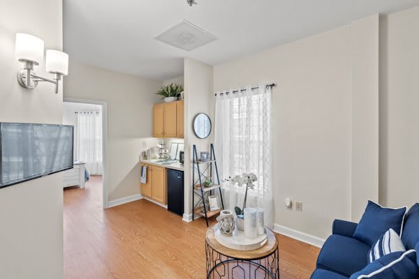 A bright and modern apartment living area with a kitchenette and wooden floors.