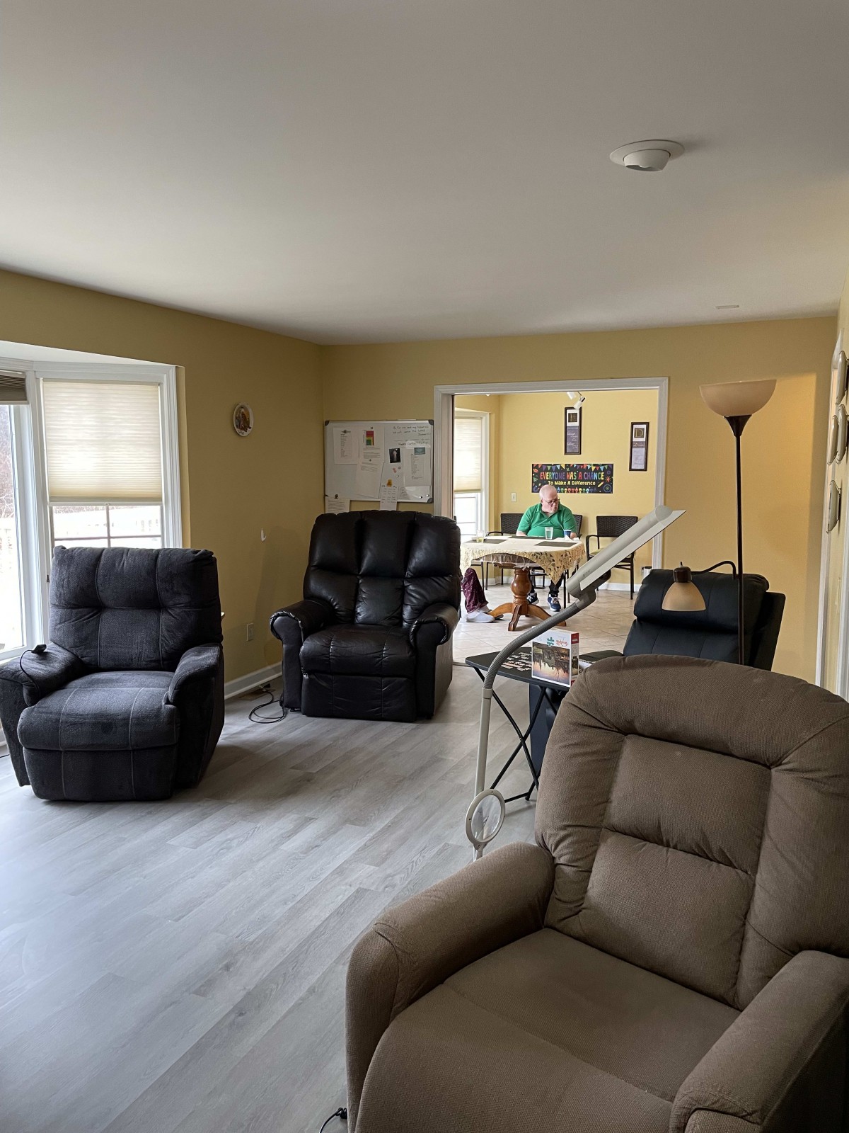 Cozy living room featuring multiple recliners and ample natural light.