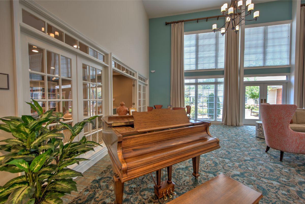 A spacious room with a grand piano, large windows, and elegant decor.