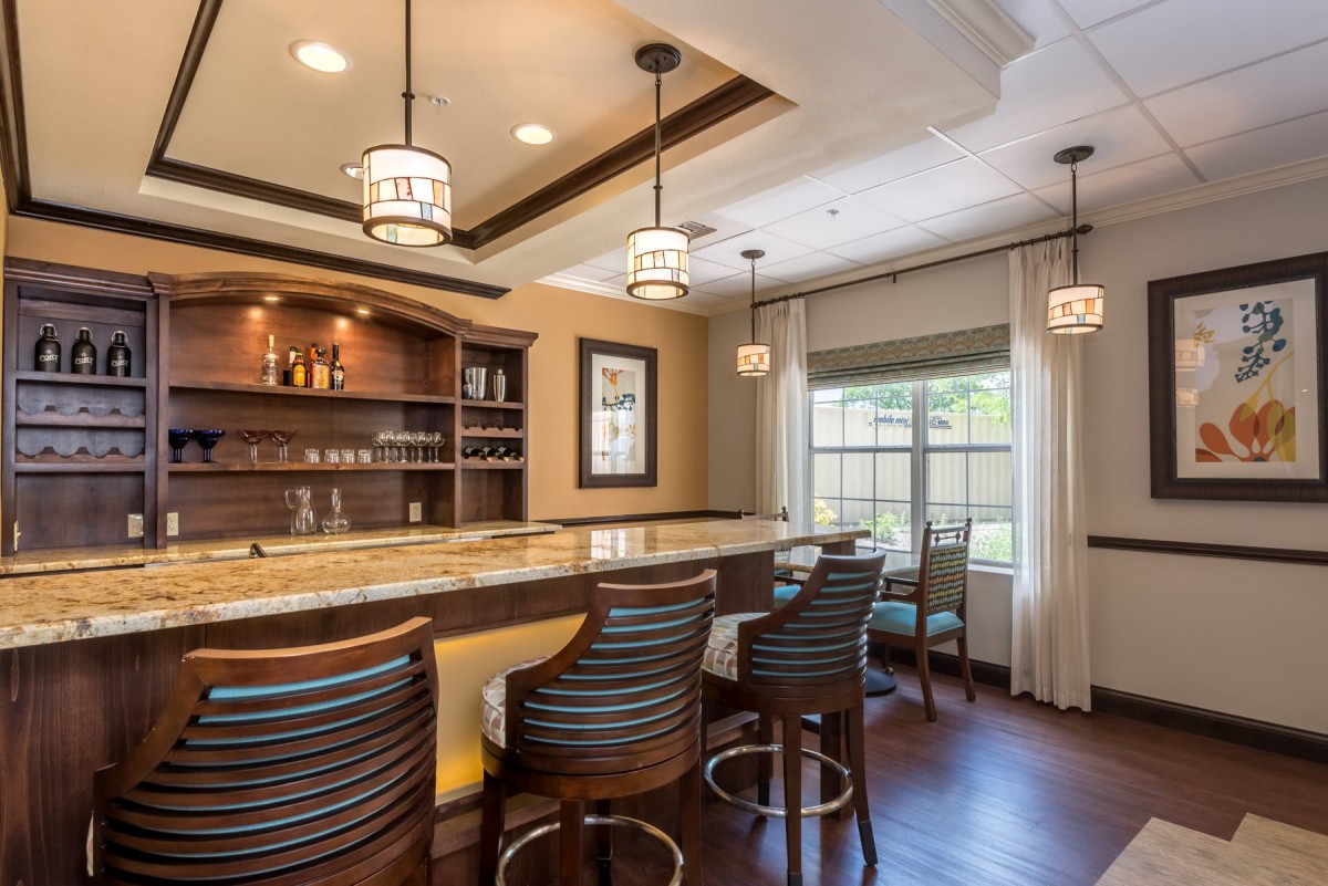 A modern bar with wooden furnishings and pendant lights, creating a cozy ambiance.