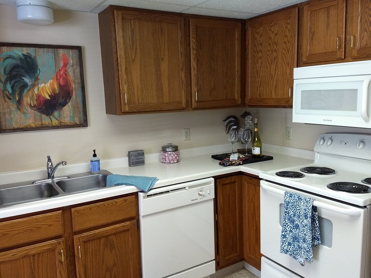 A cozy kitchen with wooden cabinets, featuring a sink, dishwasher, and appliances.