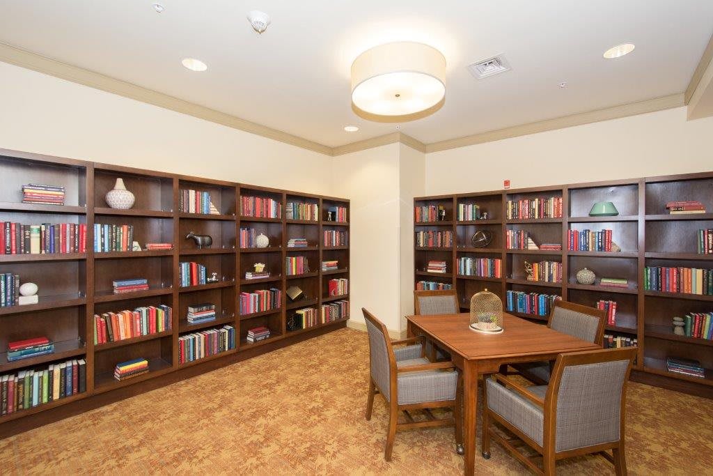 A cozy library reading area with bookshelves and a table surrounded by chairs.