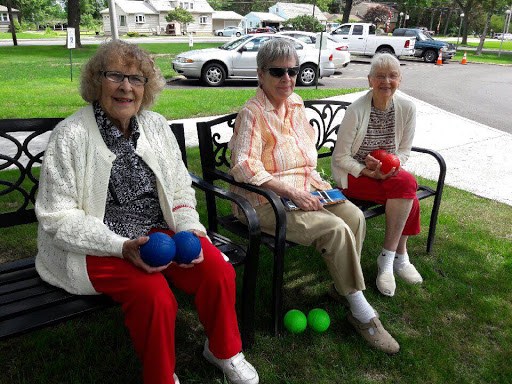Three seniors enjoying a playful moment outdoors, ready for some fun with colored balls.