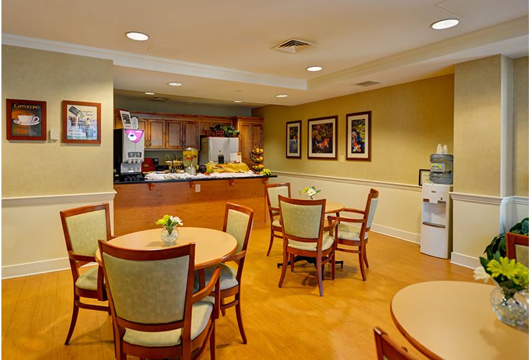 A cozy cafe-style dining area with tables and chairs, a beverage machine, and wall decorations.