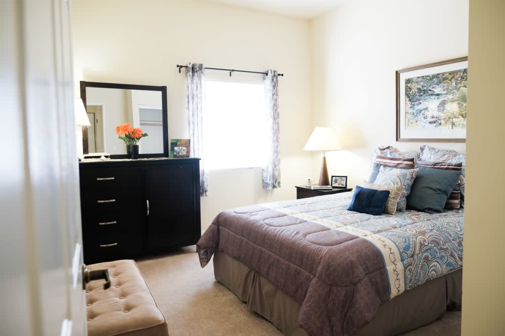 A cozy bedroom with a neatly made bed, dresser, and soft lighting.