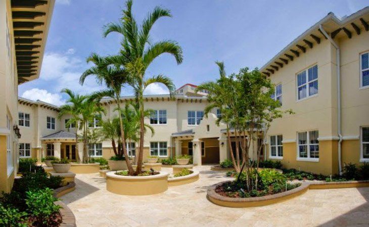 A sunny courtyard of an apartment complex with palm trees and landscaping.