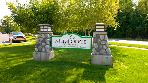 Entrance sign for MediLodge, a healthcare facility surrounded by greenery.