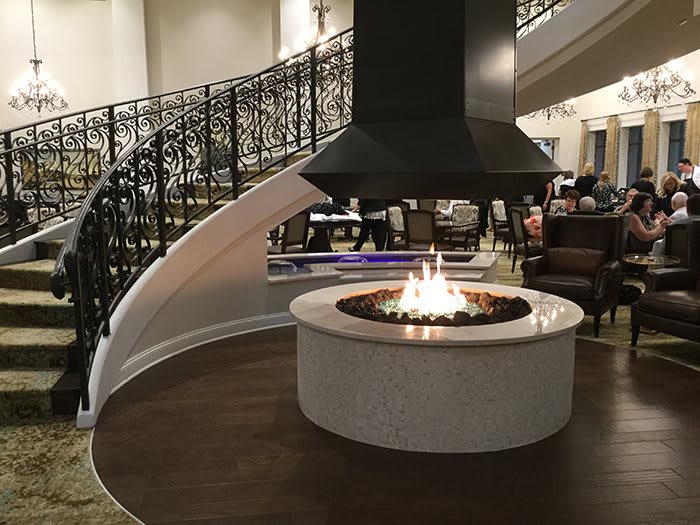 A cozy lobby with a central fireplace and elegant spiral staircase.