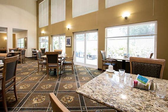 A spacious dining area with elegant decor, featuring large windows, tables, and chairs.