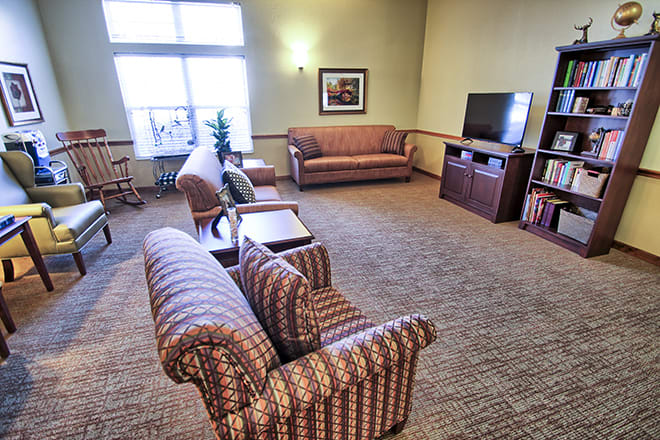 A cozy living room with sofas, a television, and large windows letting in natural light.