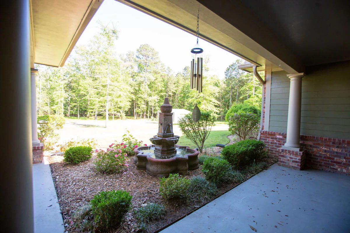 A serene garden view with a decorative fountain surrounded by lush greenery.