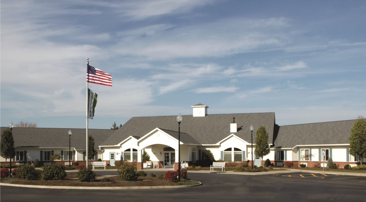 A building with an American flag in front, set against a cloudy sky.