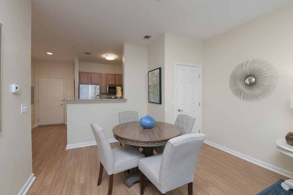 Modern dining area with a round table and upholstered chairs adjacent to an open kitchen.