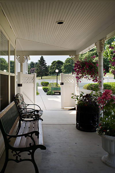 A cozy porch with benches and blooming flowers overlooks a well-maintained garden.