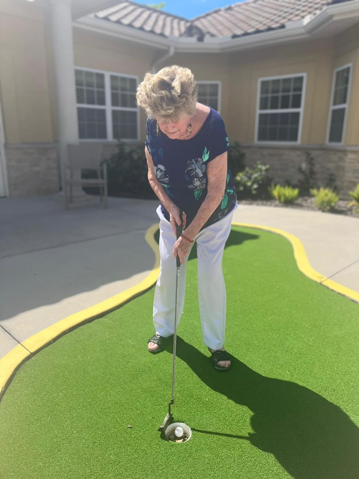A woman practicing her putting on a mini golf course outdoors.