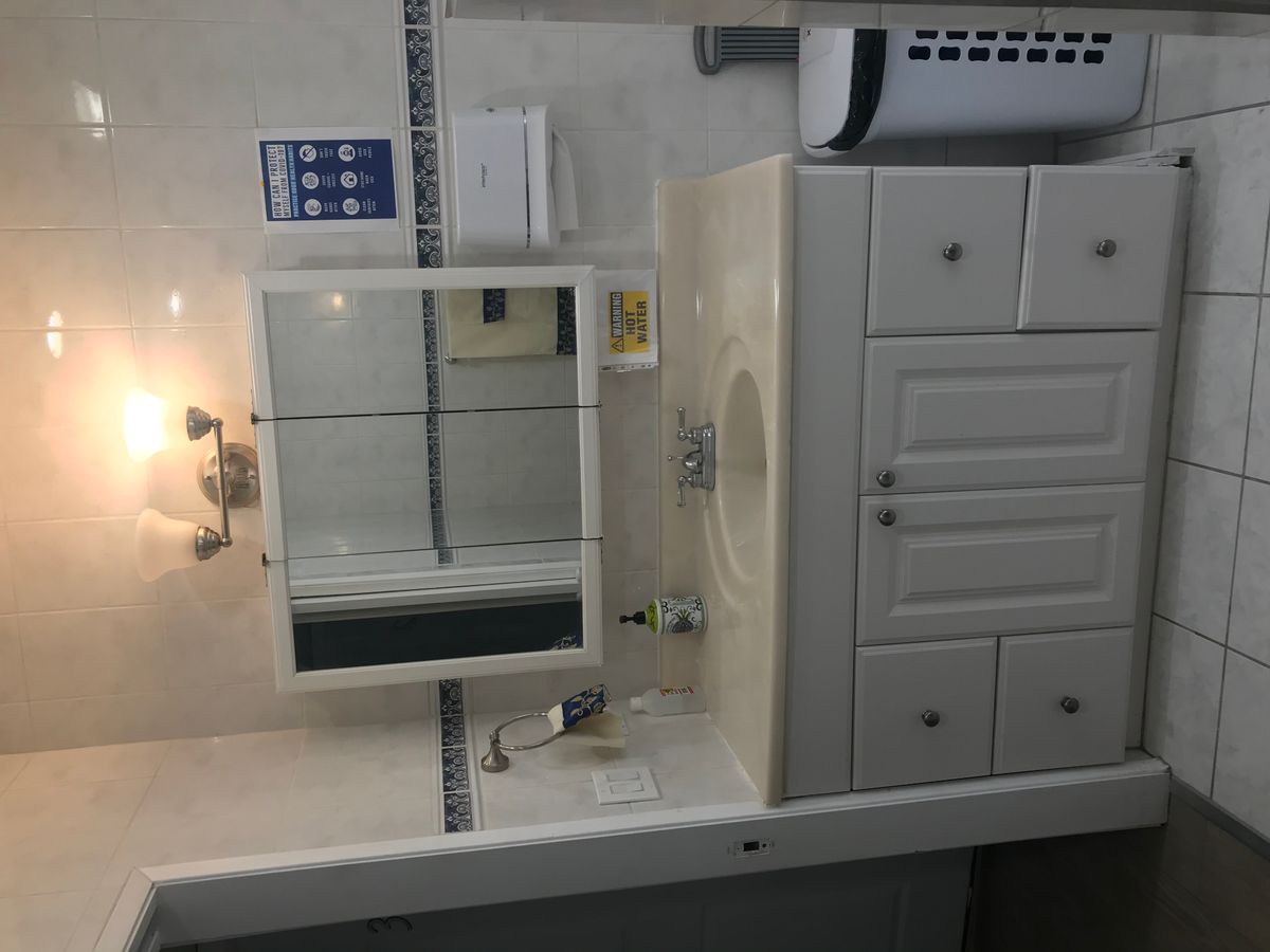 A clean and organized bathroom with a mirror, sink, and cabinet.