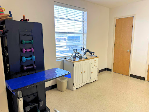 A well-lit room featuring a variety of exercise weights and a white cabinet.