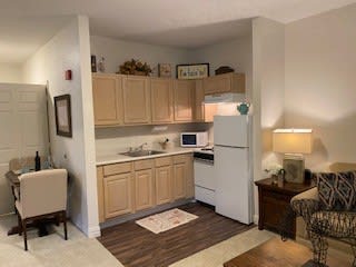 A small, cozy kitchen in an apartment with wooden cabinets and a white fridge.