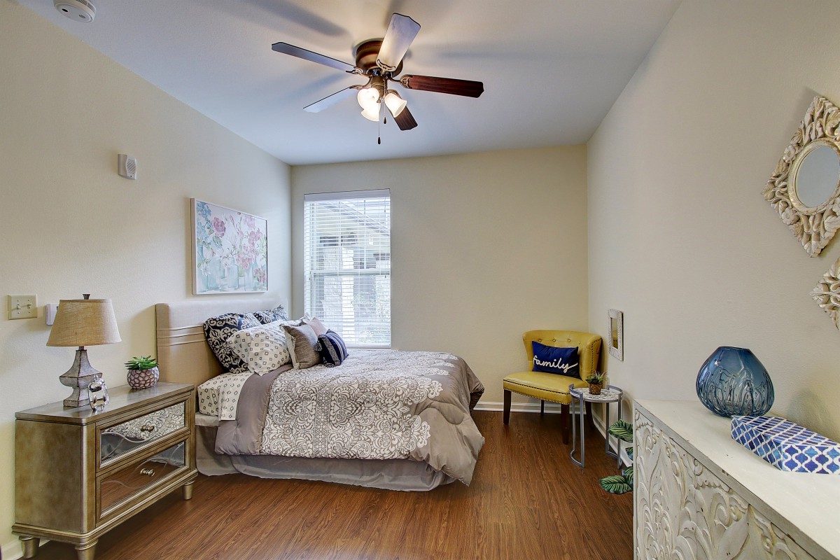 A cozy bedroom with modern decor, featuring a comfortable bed, ceiling fan, and a bright window.