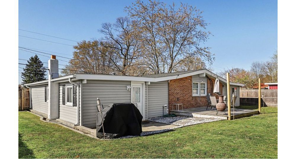 Suburban backyard with a brick house, patio, and grill.