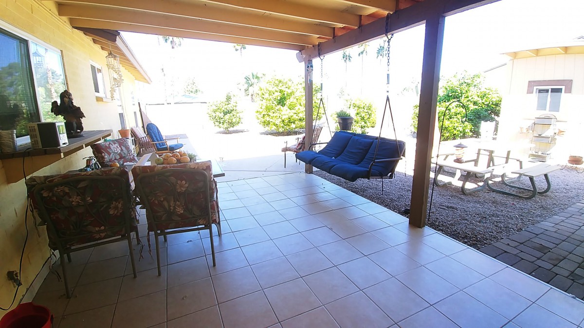 A cozy outdoor patio with a swing and seating area under a covered structure.