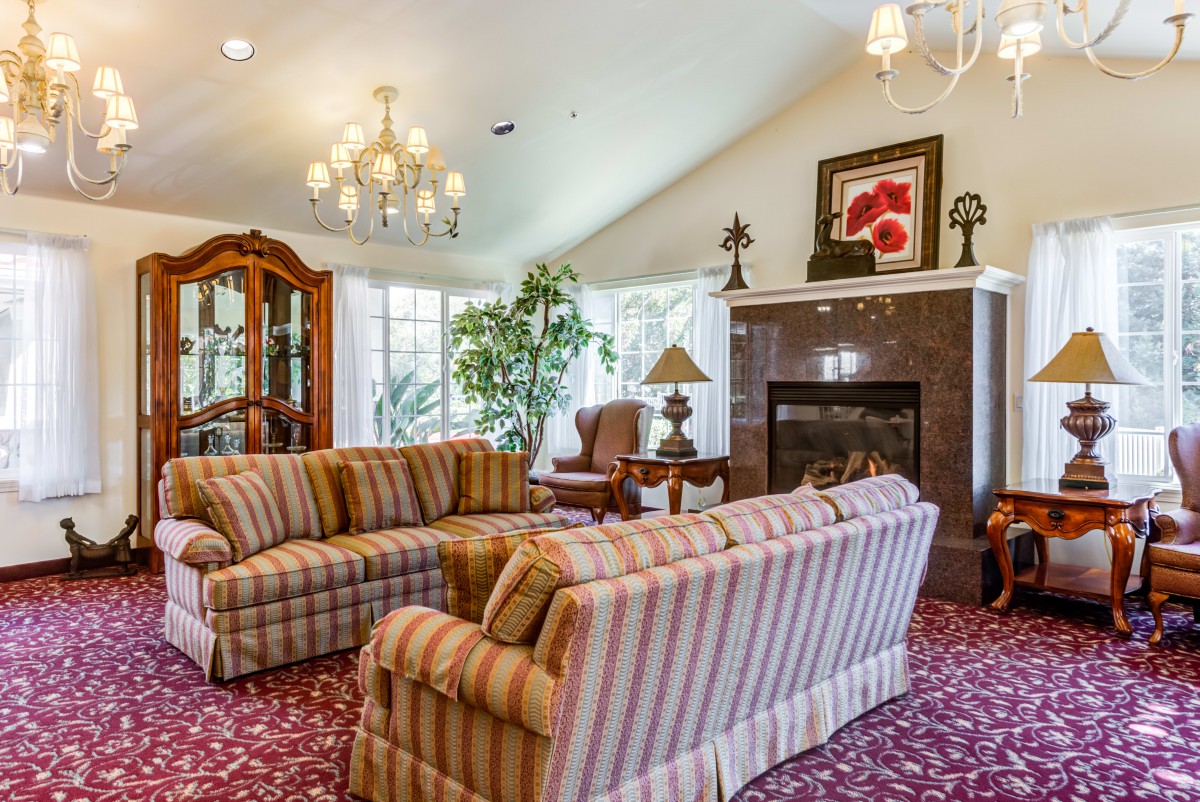 A cozy living room with striped sofas, a fireplace, and elegant chandelier lighting.